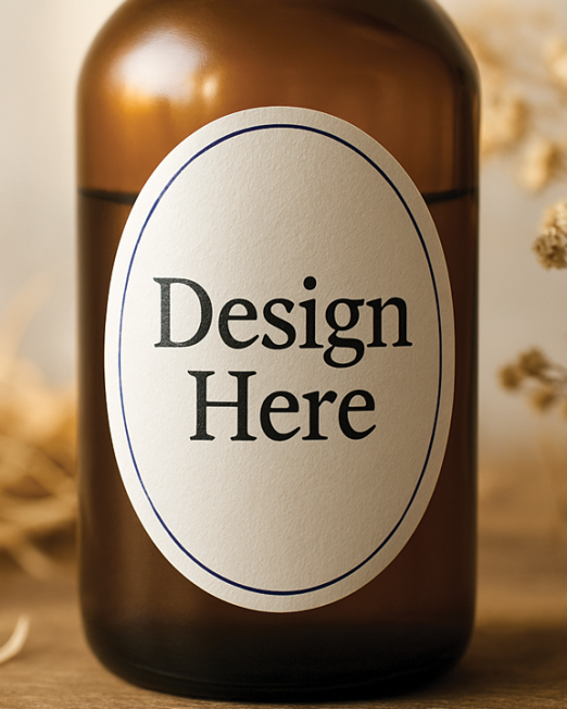 "Minimalist oval-shaped label on a glass bottle displaying 'Design Here' in distressed serif typography, surrounded by dried wildflowers and wood shavings with soft natural lighting"